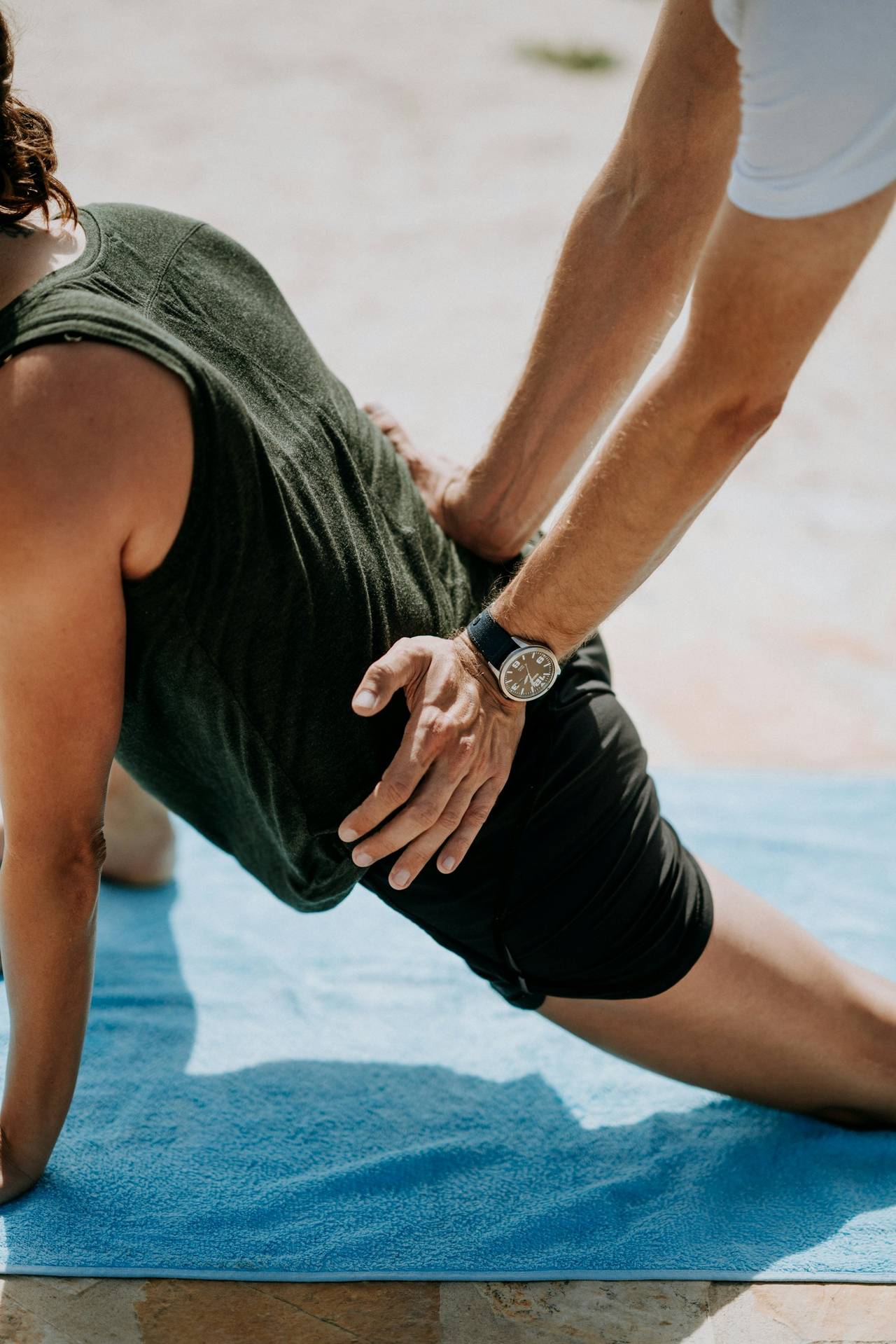 Physiotherapist assessing a patient's hip and leg on a treatment mat